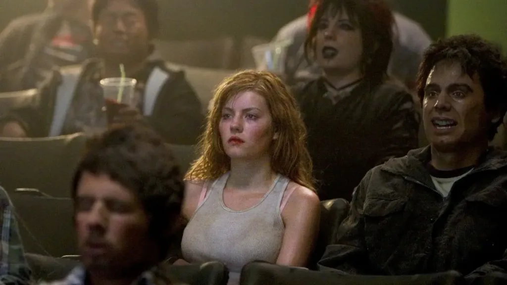 Σκηνή από την ταινία «House of Wax» (2005) με μια νεαρή γυναίκα να κάθεται ανήσυχη σε σκοτεινή αίθουσα κινηματογράφου, περιτριγυρισμένη από άλλους θεατές.