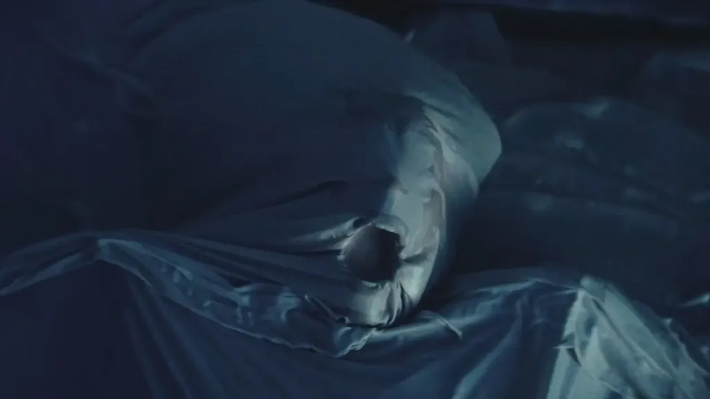 Μαξιλάρι που καλύπτει ένα πρόσωπο, με μια έντονη τρύπα στη μέση, σκηνή τρόμου από την ταινία “Nanny” (2022).