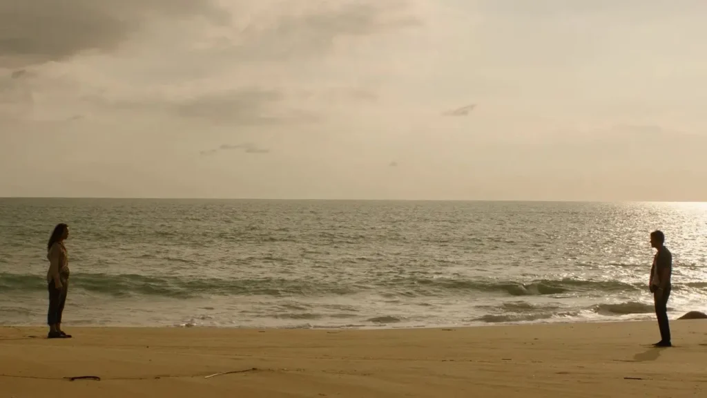 Δύο ναυαγοί στέκονται αντικριστά σε μεγάλη απόσταση σε έρημη παραλία, με τη θάλασσα στο βάθος κάτω από συννεφιασμένο, χρυσαφένιο ουρανό, δημιουργώντας αίσθηση έντασης και μοναξιάς. Σκηνή από την ταινία τρόμου «Send Help».
